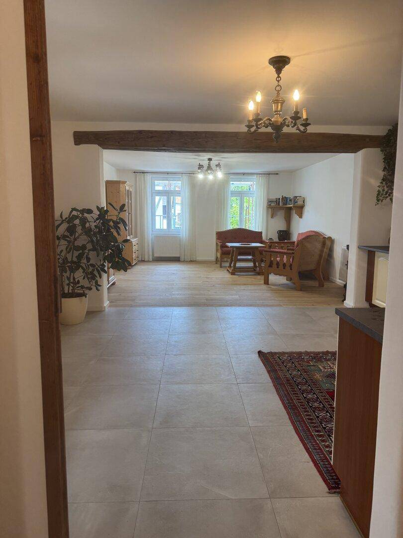 Offener Wohnbereich mit Fliesen- und Holzboden, verbunden mit einem gemütlichen Wohnzimmer.