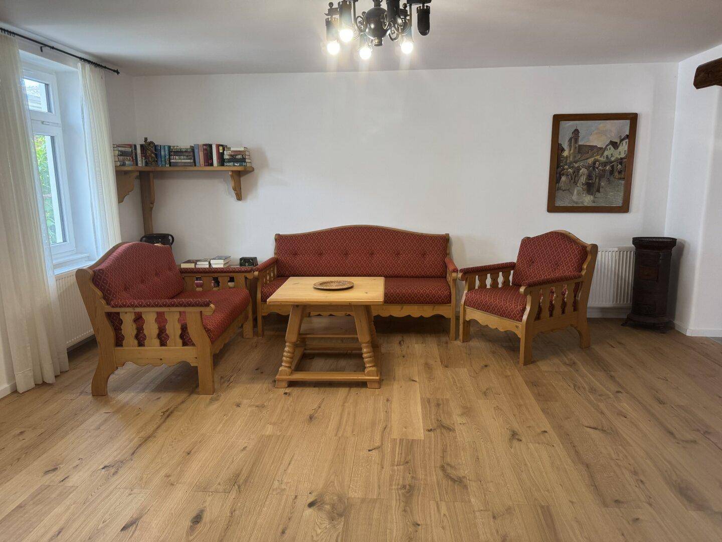 Gemütliches Wohnzimmer mit traditionellen Holzmöbeln, rotem Polster und Holzboden.
