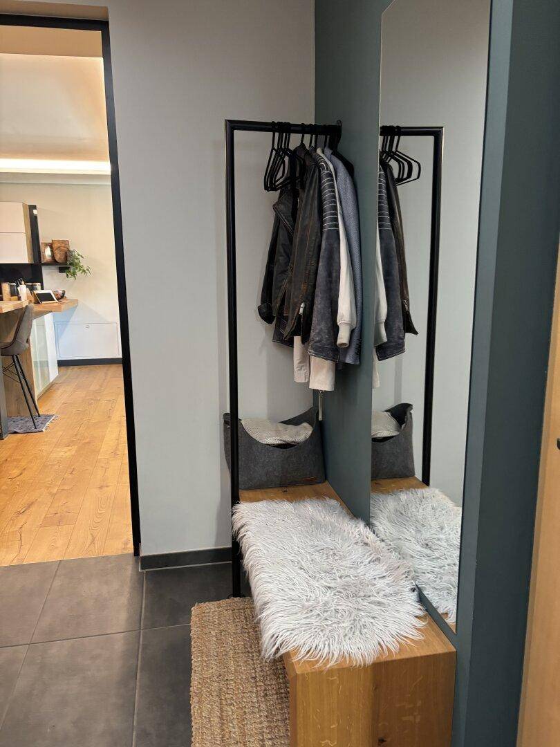 Eingangsbereich mit Garderobe, großem Spiegel und einer Sitzbank.