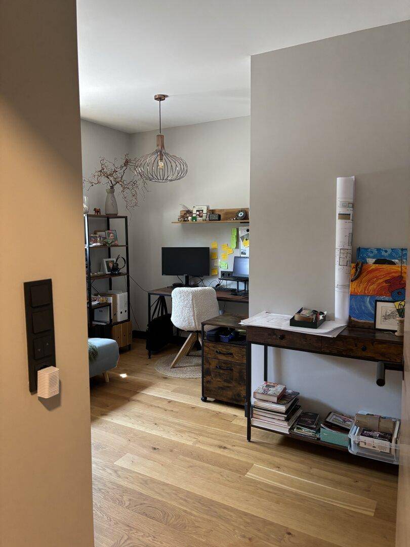 Heller Arbeitsbereich mit Schreibtisch, Regalen und Holzboden, ideal für konzentriertes Arbeiten.