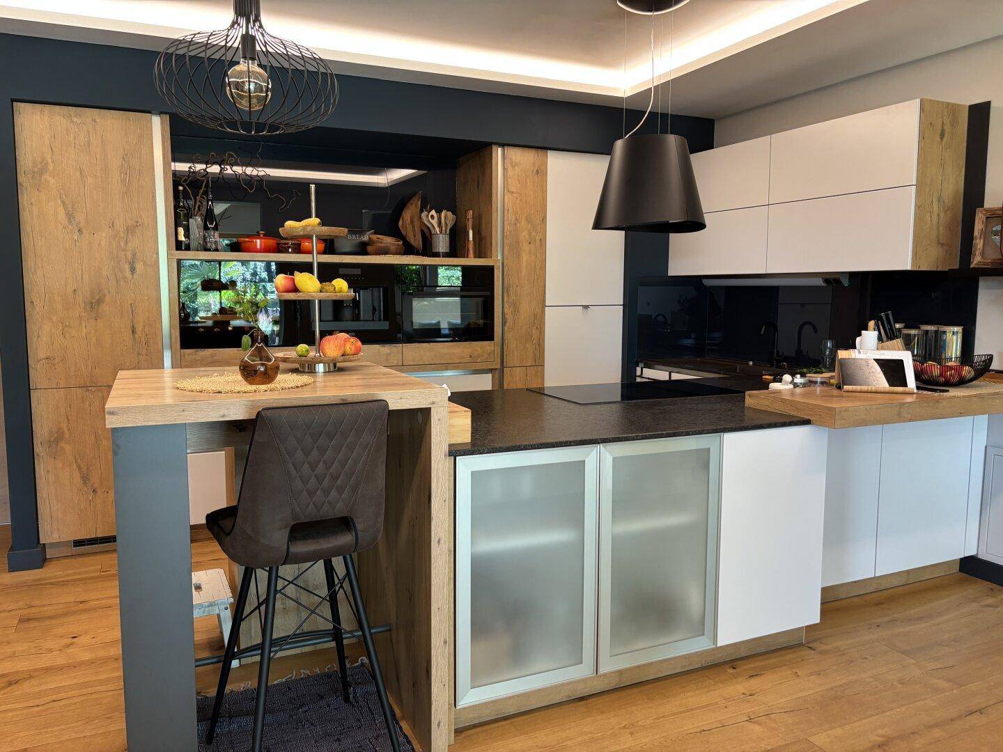 Moderne Küche mit Kochinsel, Frühstücksbar, Holz- und weißen Schränken sowie Einbaugeräten.