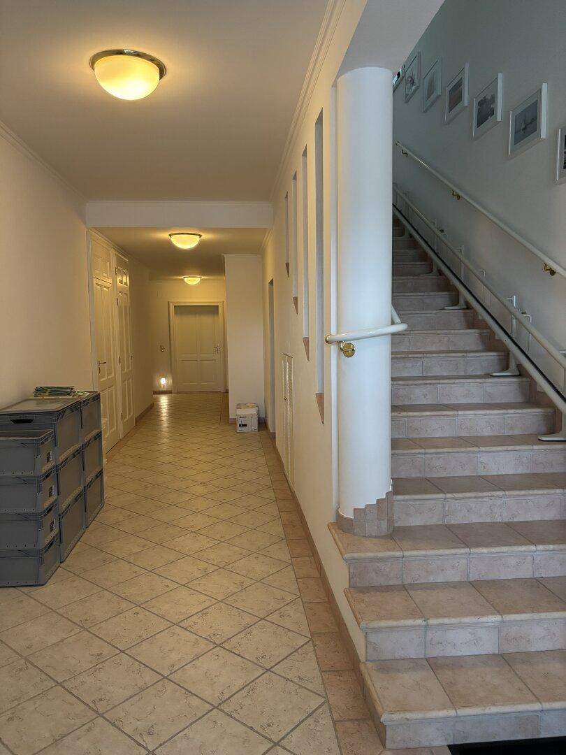 Geräumiger Flur mit gefliestem Boden und einer breiten Treppe zum Obergeschoss.