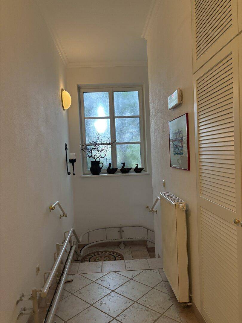 Treppenabsatz mit Fenster, gefliestem Boden und integrierten Schränken.
