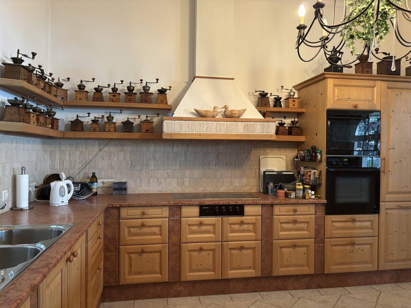 Detailansicht der traditionellen Holzküche mit Kochfeld, Backofen und zahlreichen dekorativen Kaffeemühlen.