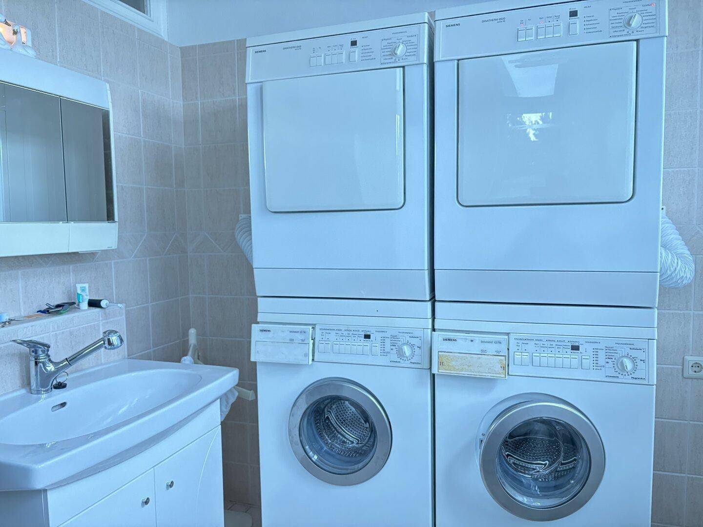 Praktischer Hauswirtschaftsraum mit Waschmaschine, Trockner und Waschbecken.