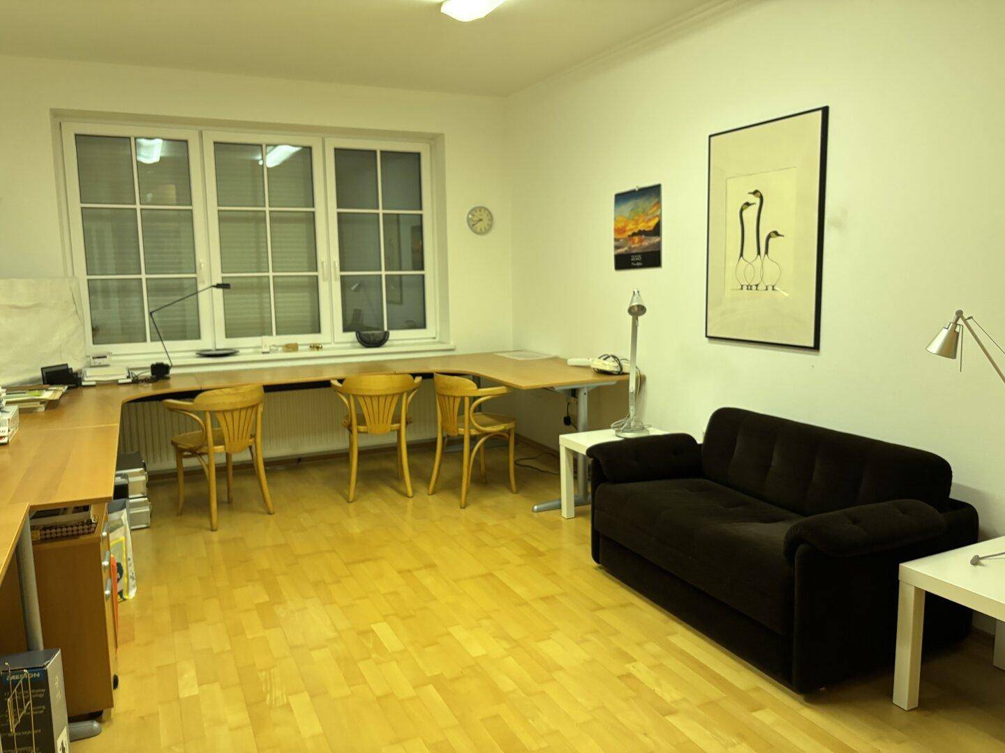 Geräumiges Büro mit Holzboden, großem Schreibtisch und bequemer Couch.