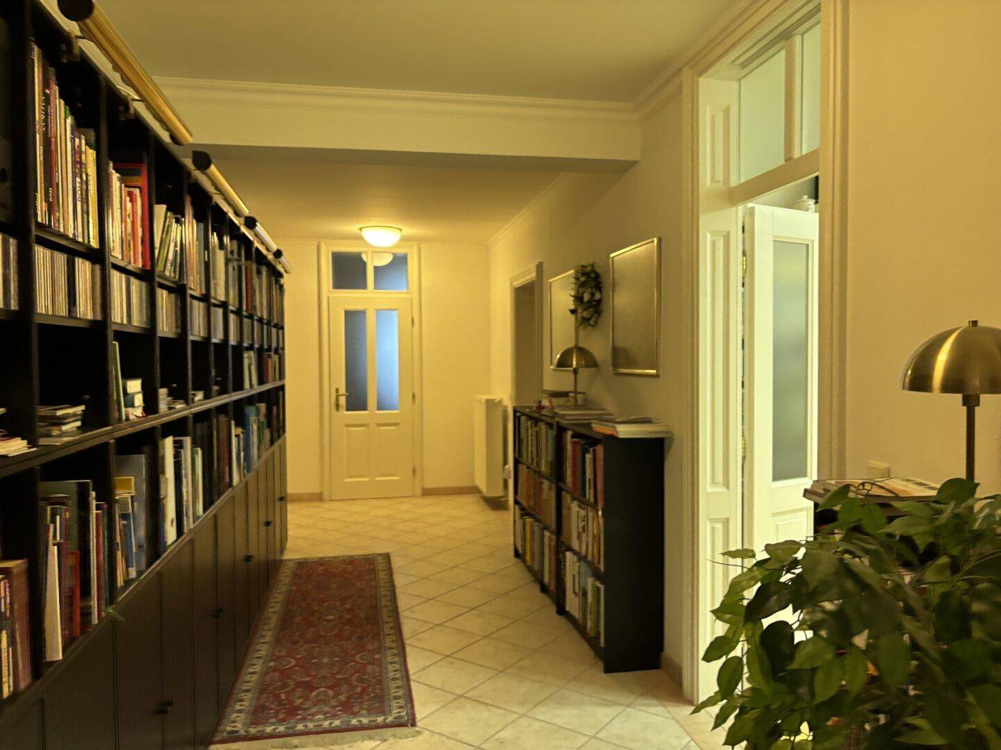 Heller Flur mit Bücherregalen und Zugang zu weiteren Räumen.