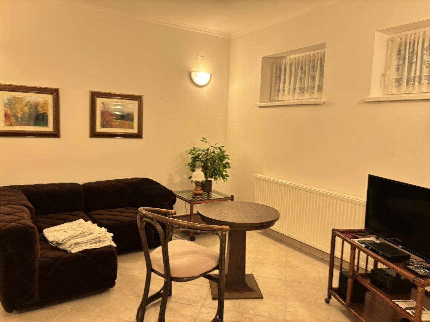 Gemütlicher Wohnbereich mit Sofa, kleinem Tisch und Fernseher, ideal zum Entspannen.