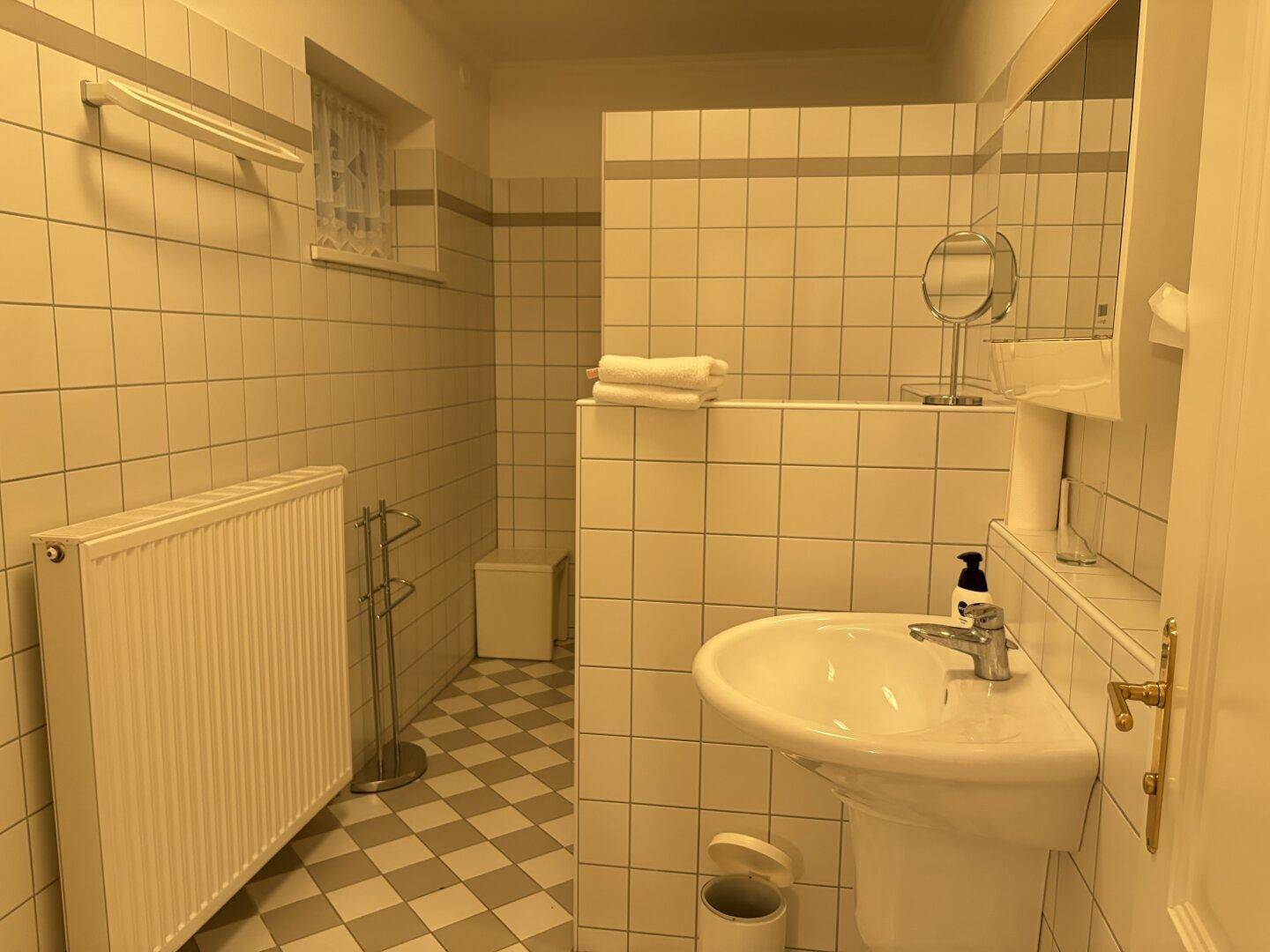 Helles Badezimmer mit Fliesen, Waschbecken und Heizkörper, im klassischen Stil.