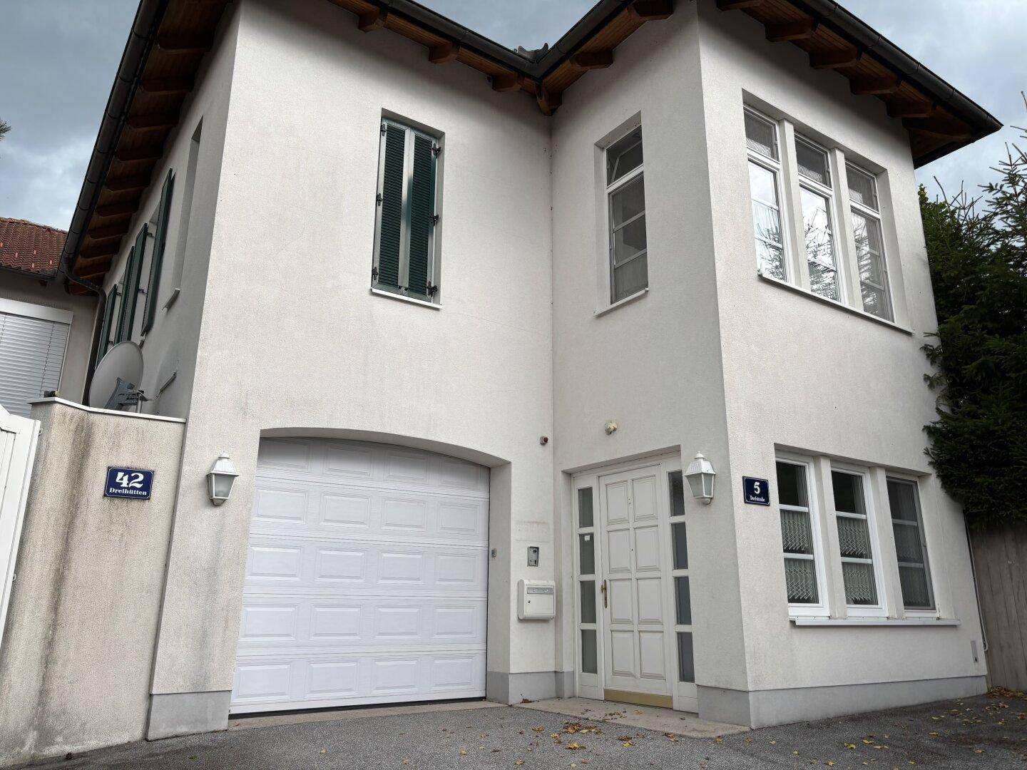 Vorderansicht eines modernen weißen Hauses mit integrierter Garage und Haupteingang.