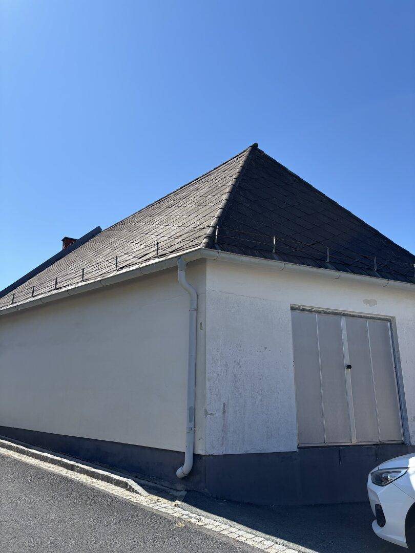 Garage mit Satteldach und weißer Fassade neben der Straße, funktional und gut erhalten.