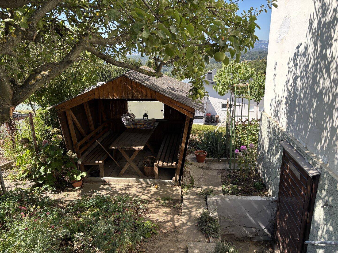 Gartenbereich mit Holzpavillon, Esstisch und Obstbäumen, ideal für entspannte Stunden im Freien.