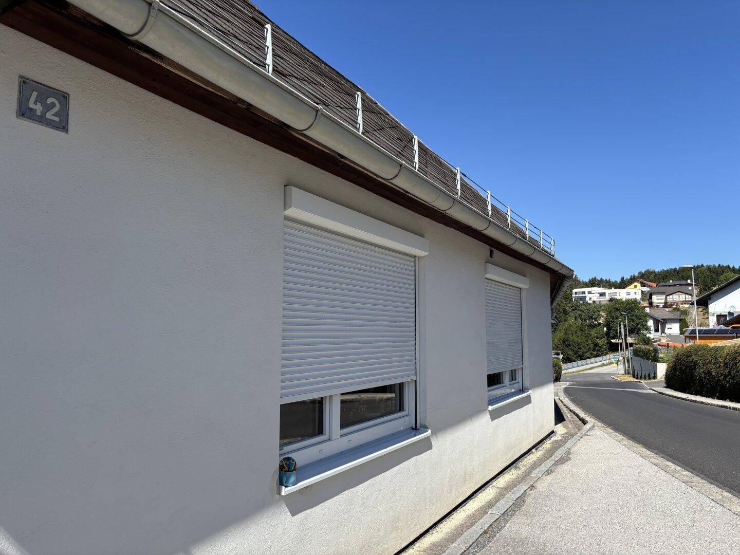 Seitenansicht des Hauses mit Rollläden an den Fenstern und Hausnummer 42, an einer Straße gelegen.