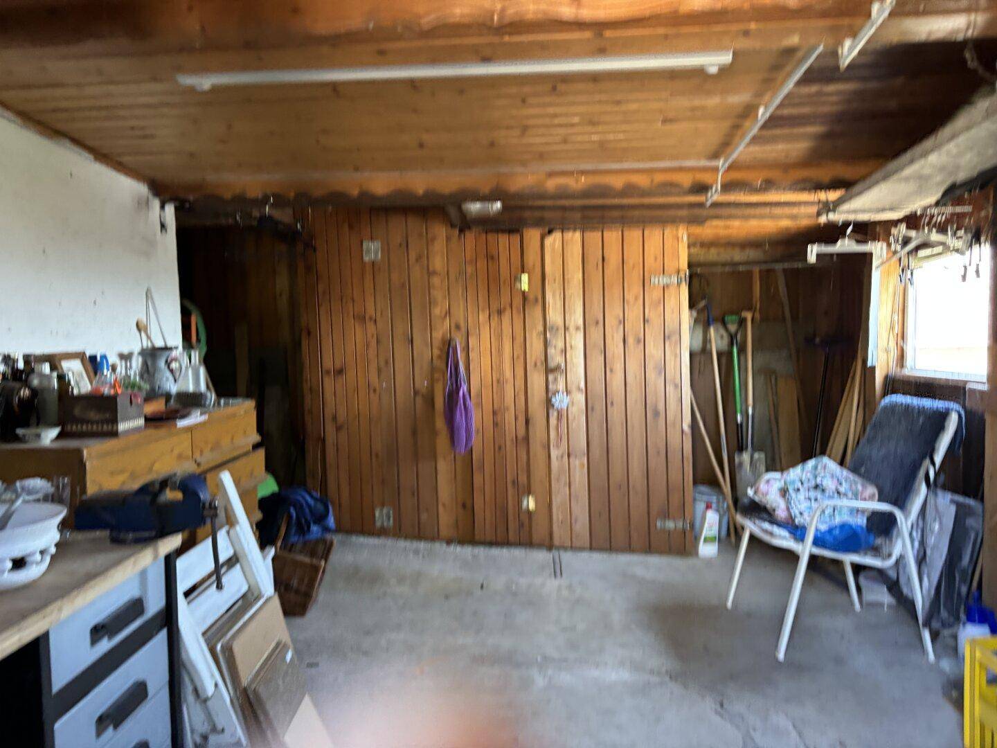 Innenansicht einer Garage oder Werkstatt mit Holzwänden und Werkbank, vielseitig nutzbar.