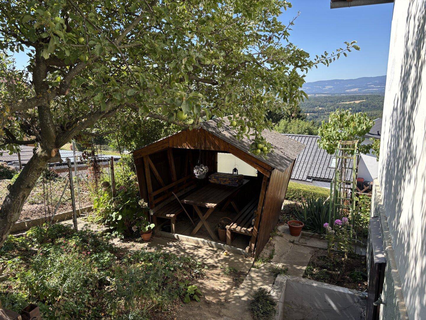 Gemütlicher Holzpavillon mit Sitzgelegenheiten im Grünen und weitem Blick auf die Landschaft.