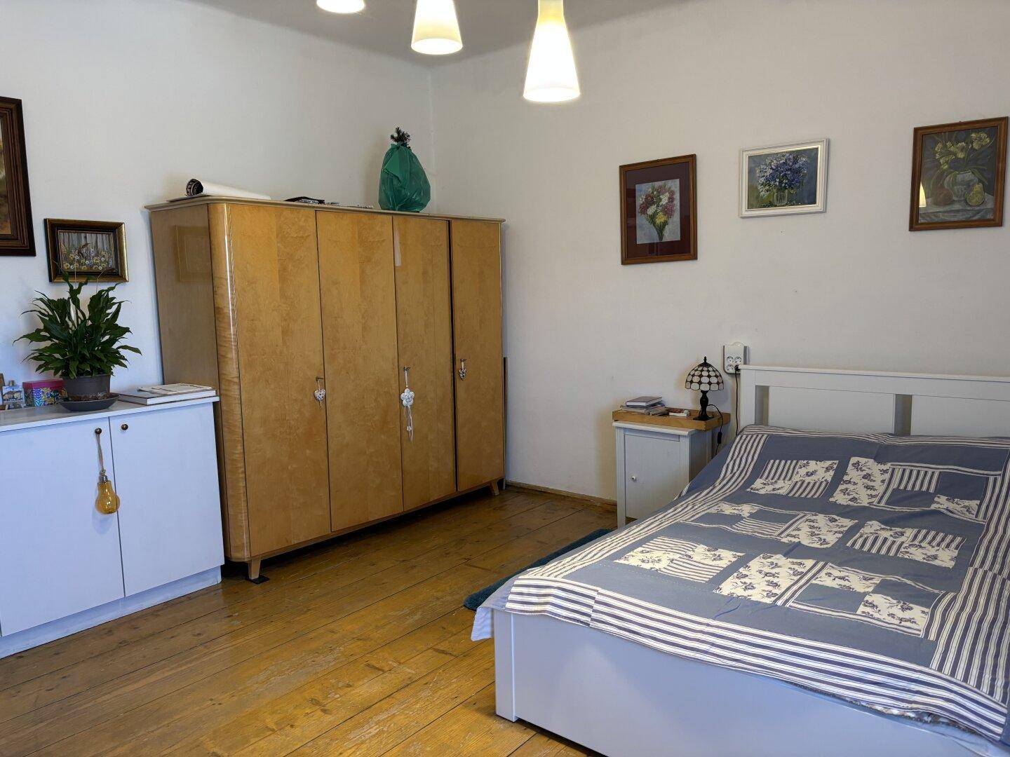Schlafzimmer mit Holzboden, großem Kleiderschrank und einem Doppelbett, funktional eingerichtet.