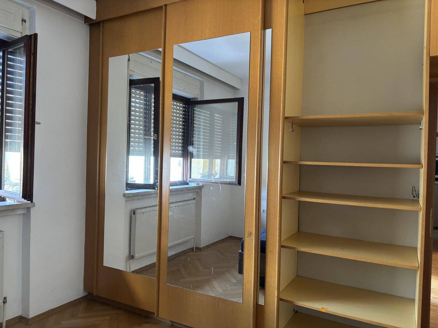 Schlafzimmer mit einem großen Einbauschrank mit Spiegeltüren und einem Fenster.