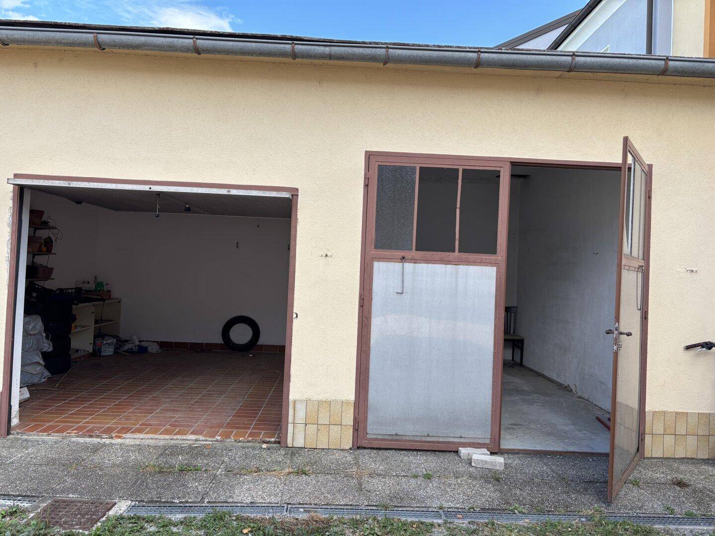Zwei offene Garagentore eines Gebäudes mit Fliesenboden und Lagerraum.