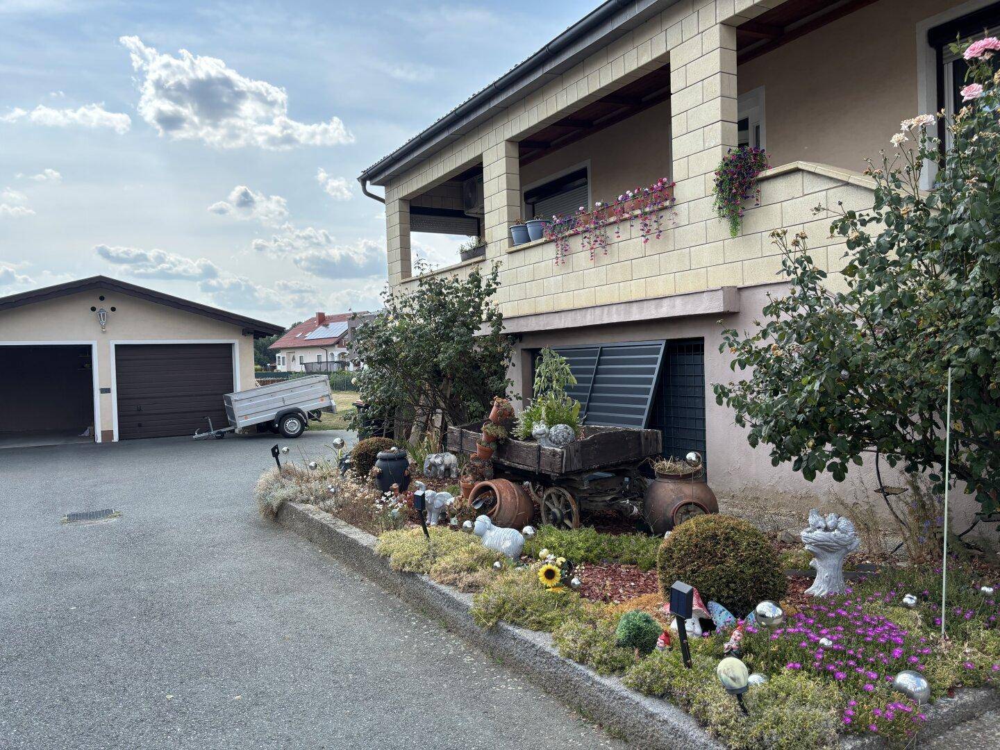 Ansicht des Hauses mit Vorgarten, Garage und Zufahrt unter bewölktem Himmel.