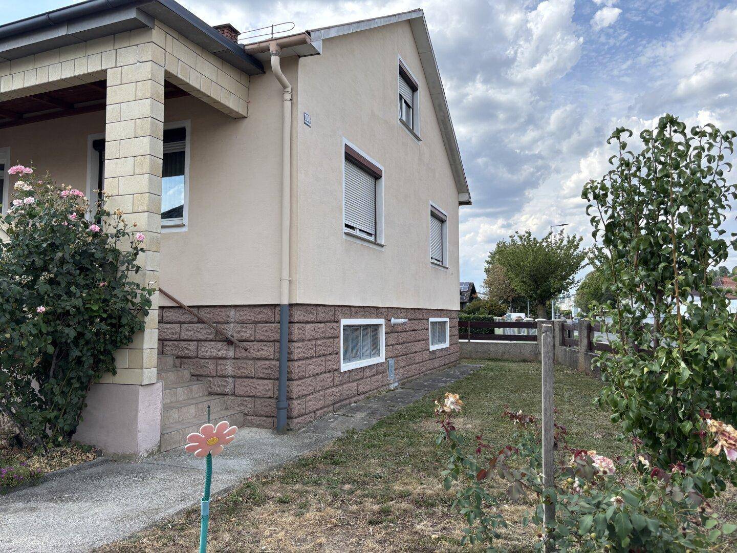 Seitenansicht des Hauses mit Rollläden und einem kleinen Rasenbereich.