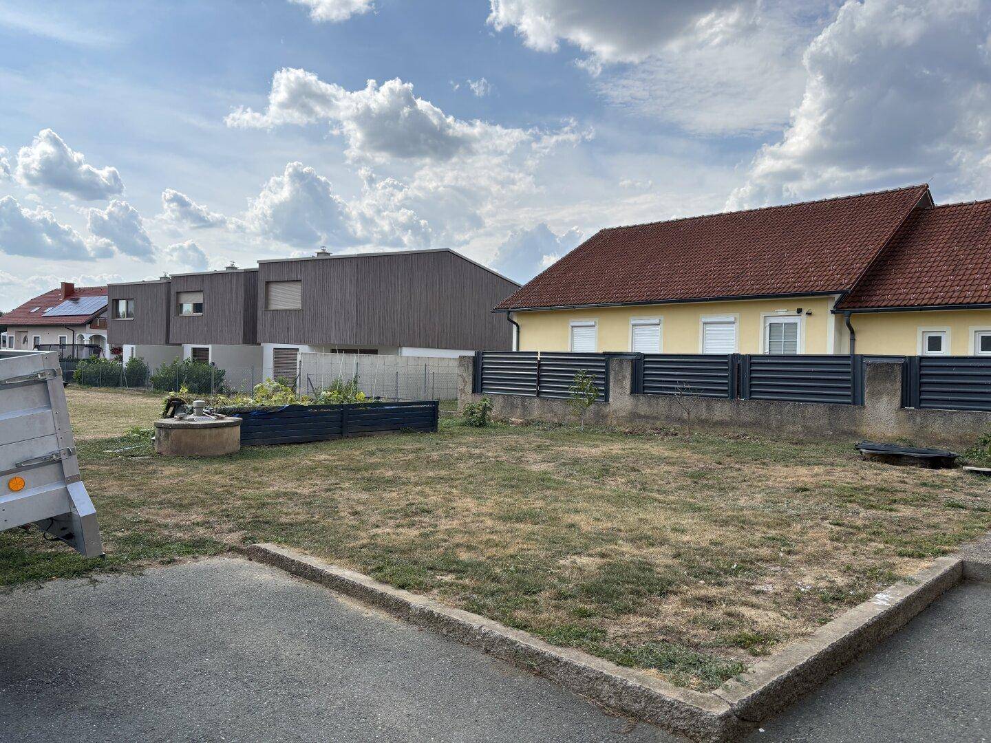 Großer Gartenbereich mit Hochbeeten und Blick auf benachbarte Häuser.