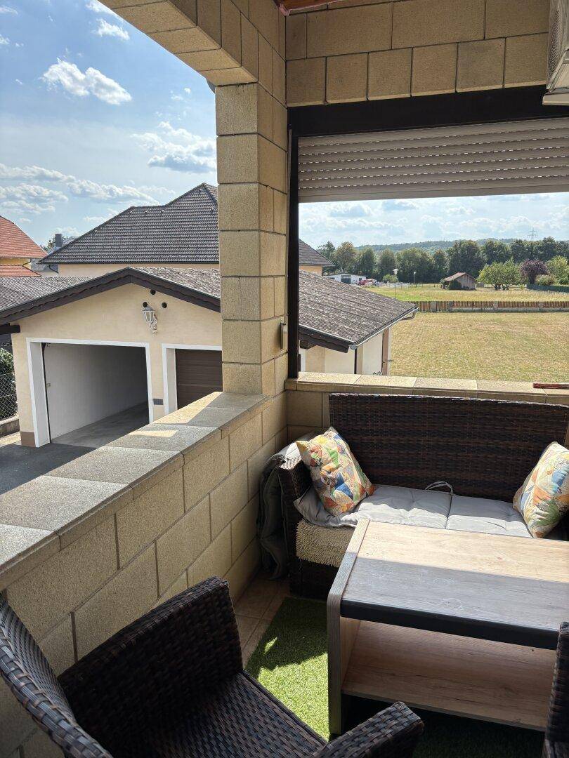 Balkon mit Sitzgelegenheiten und weitem Blick über die Landschaft und die Garage.