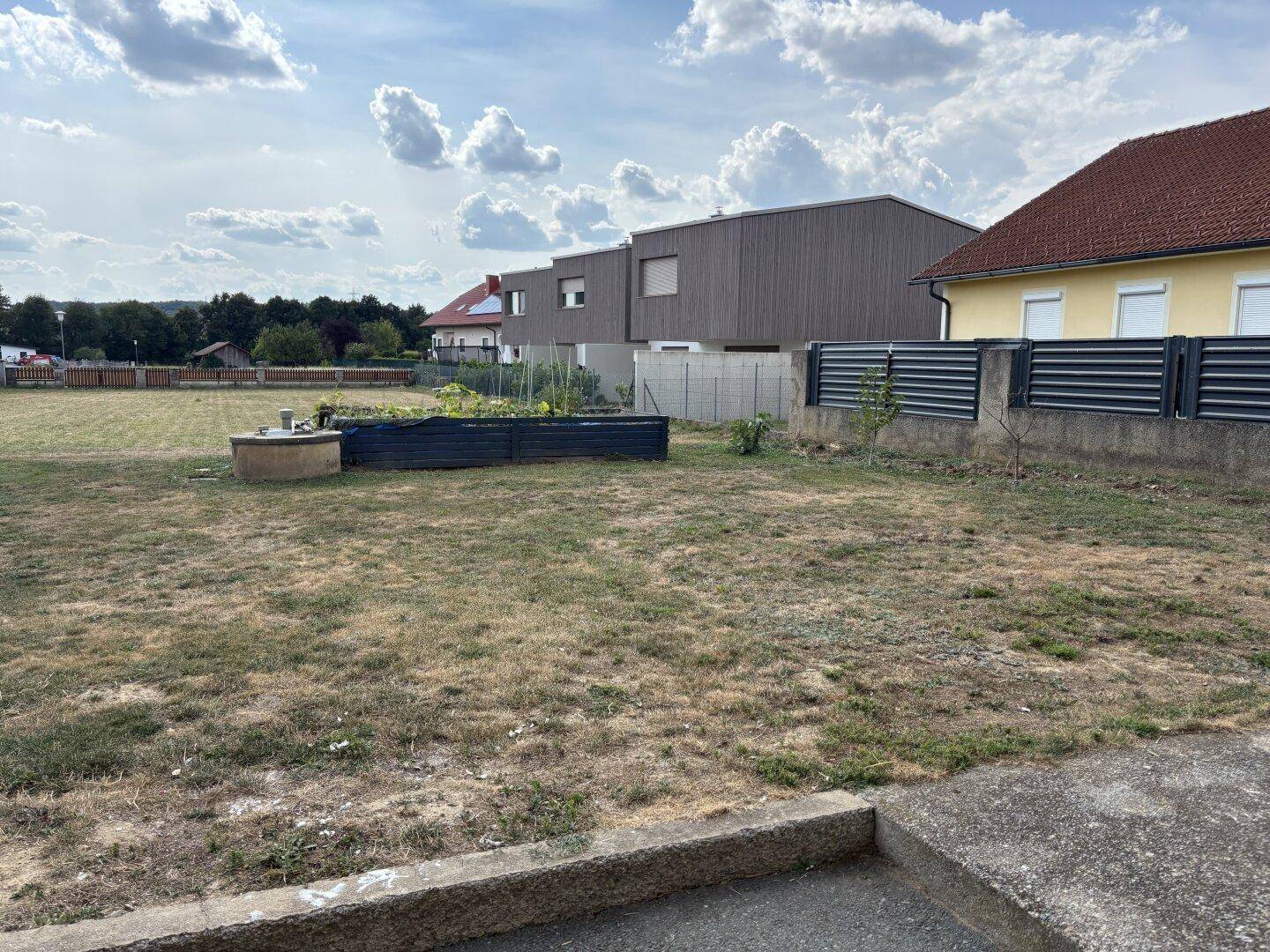 Weitläufiger Gartenbereich mit Hochbeeten und Blick auf die umliegende Bebauung.