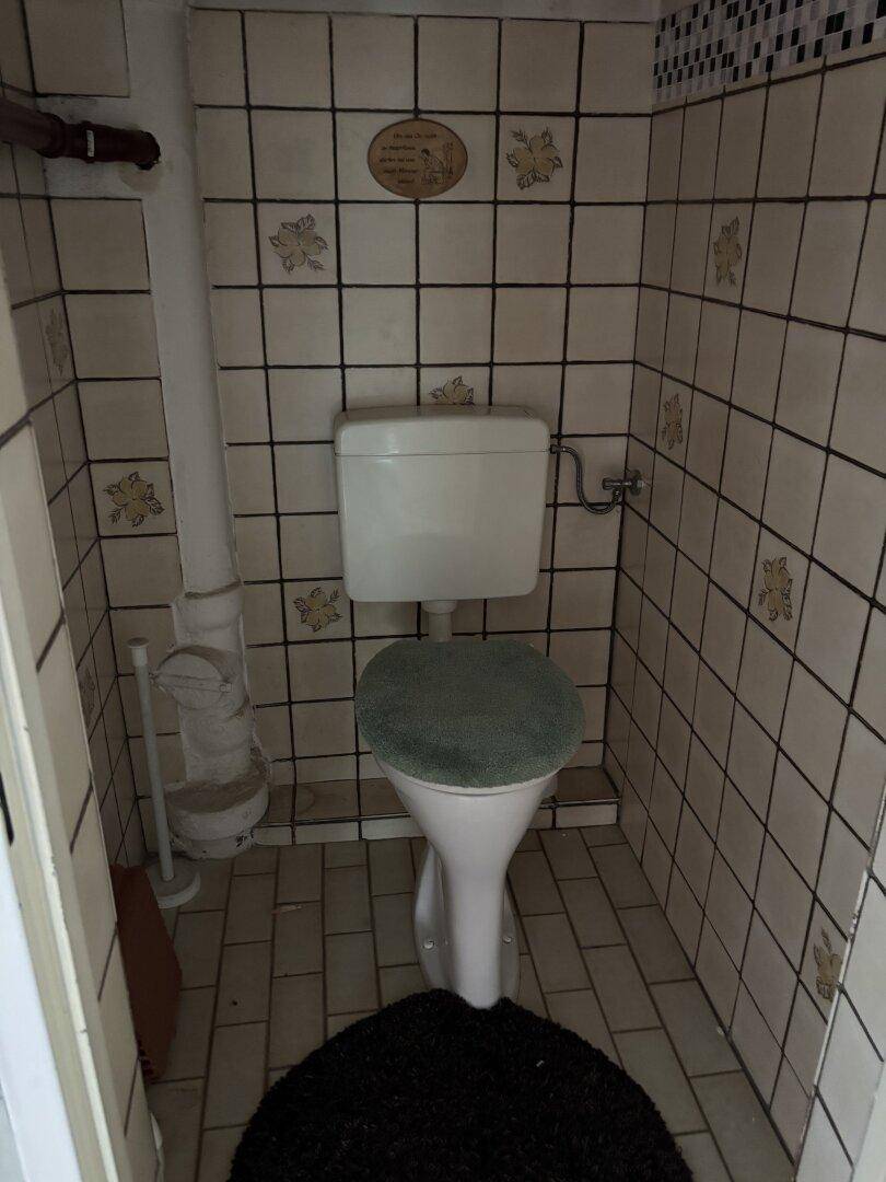 Kleines WC im Keller mit Fliesen und einfacher Ausstattung.