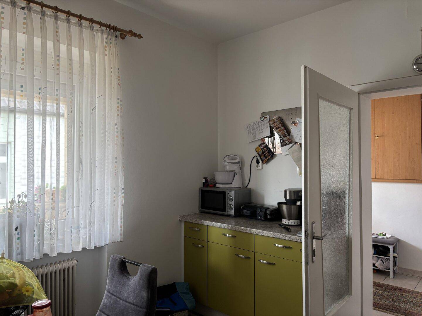 Küchenbereich mit Mikrowelle, Kaffeemaschine und einem kleinen Esstisch am Fenster.