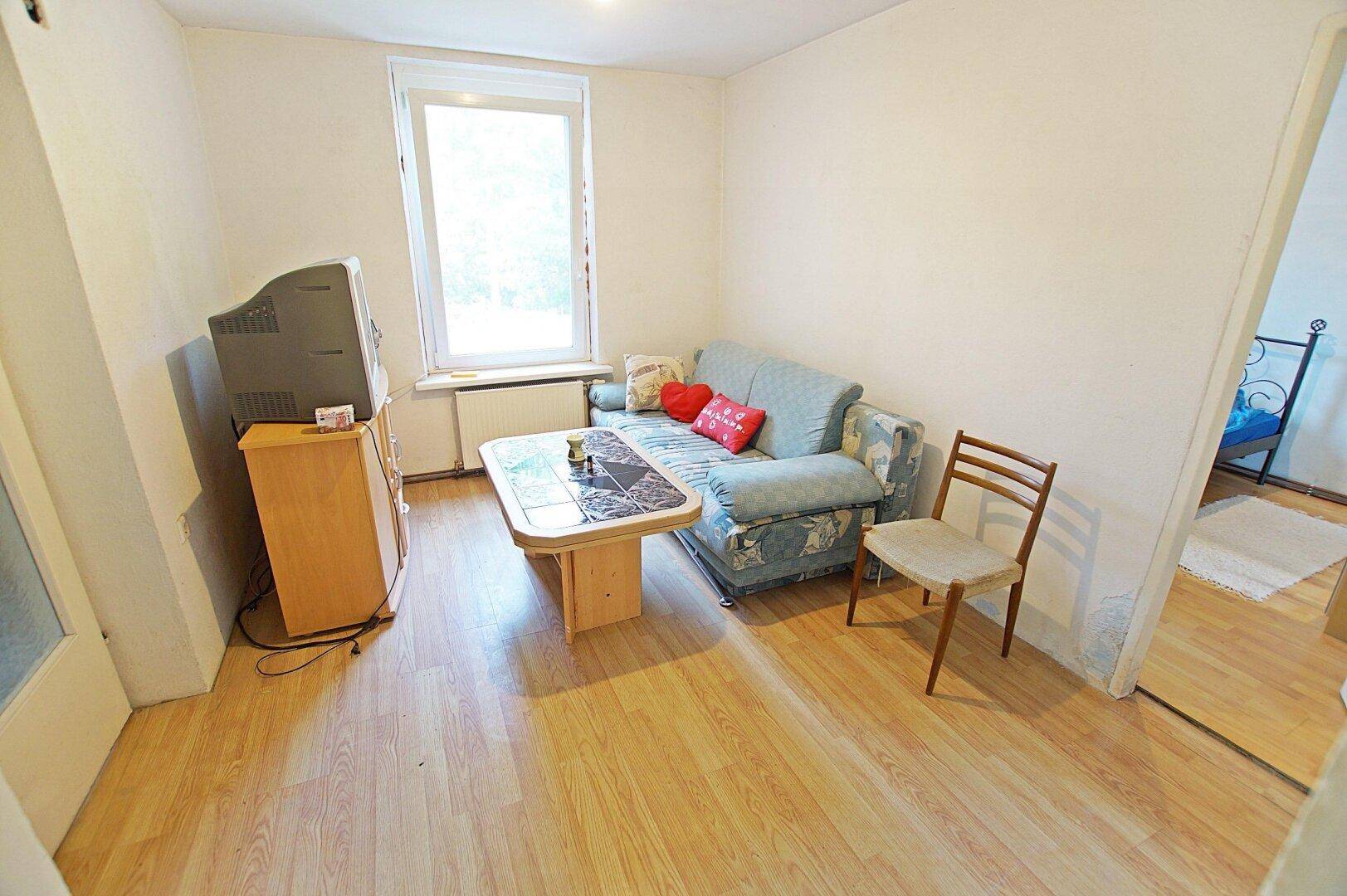 Kleines Wohnzimmer mit Sofa, Couchtisch und Laminatboden, ideal für gemütliche Stunden.