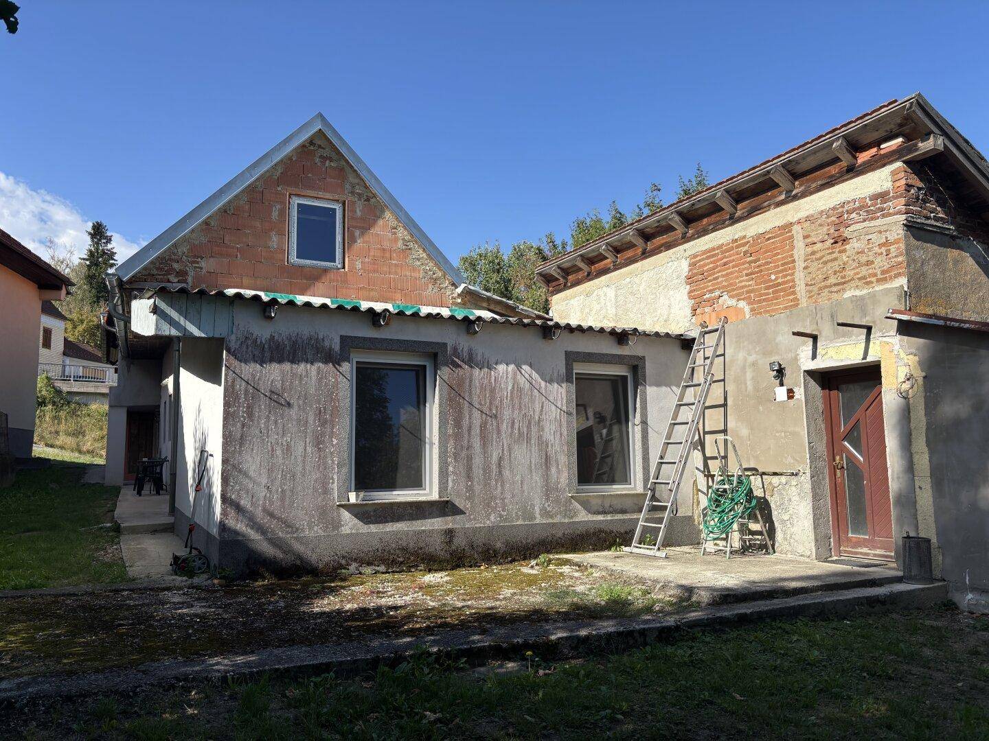 Rückseite des Hauses mit Anbau und sichtbaren Bauarbeiten bei Sonnenschein.