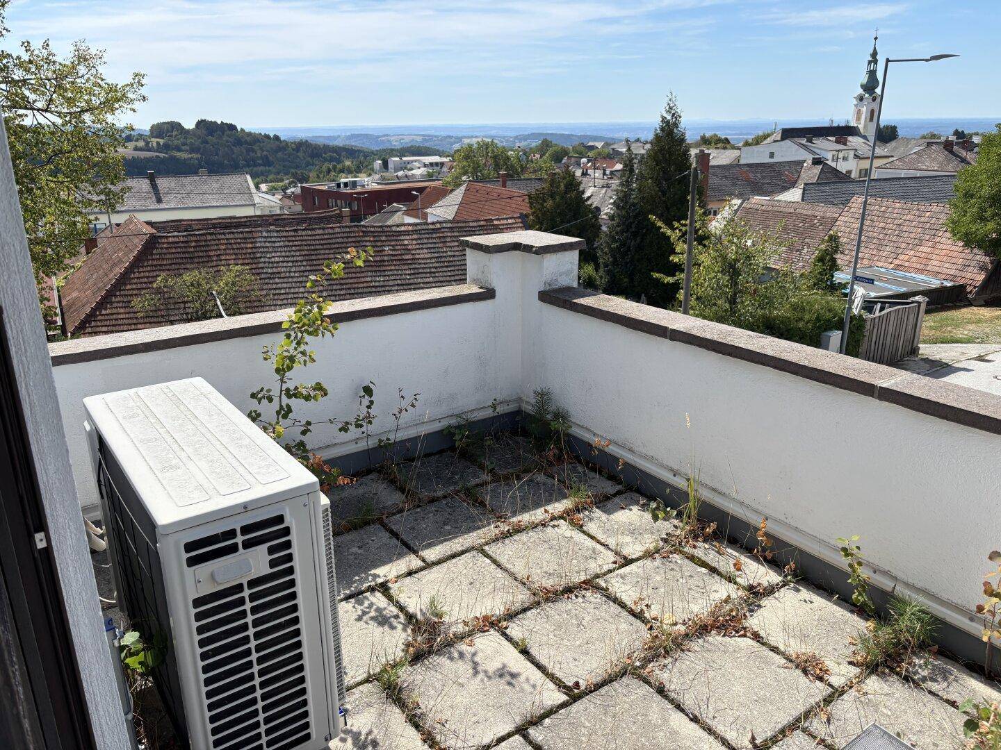 Dachterrasse mit Steinplatten, Klimaanlage und weitem Blick über die Stadt.