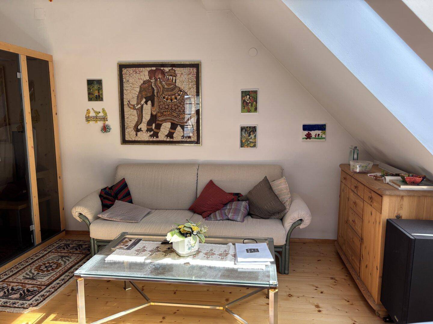 Gemütliches Wohnzimmer im Dachgeschoss mit Sofa, Couchtisch und schrägen Wänden.