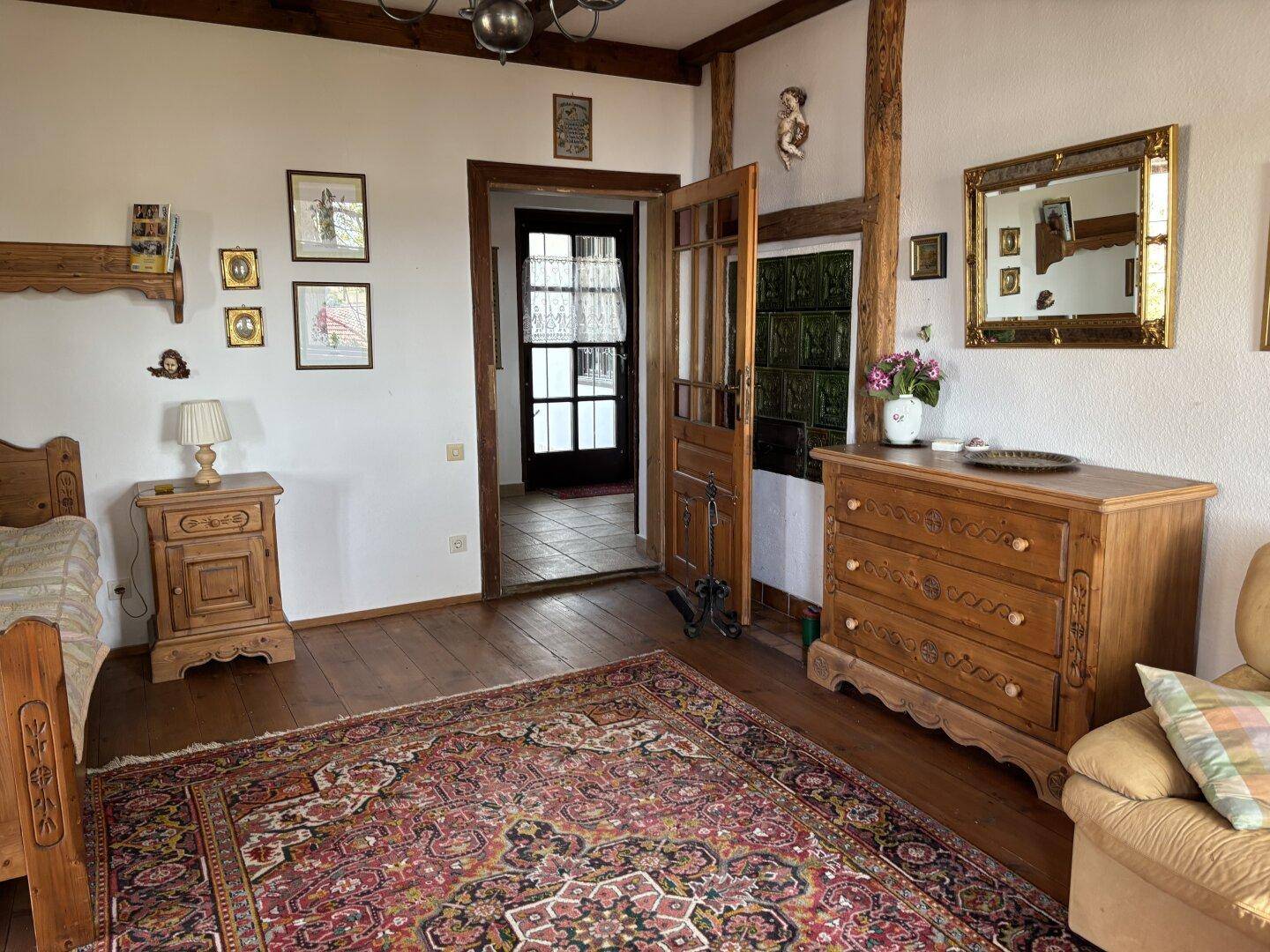 Helles Schlafzimmer mit Holzboden, Teppich und Zugang zu einem weiteren Raum.