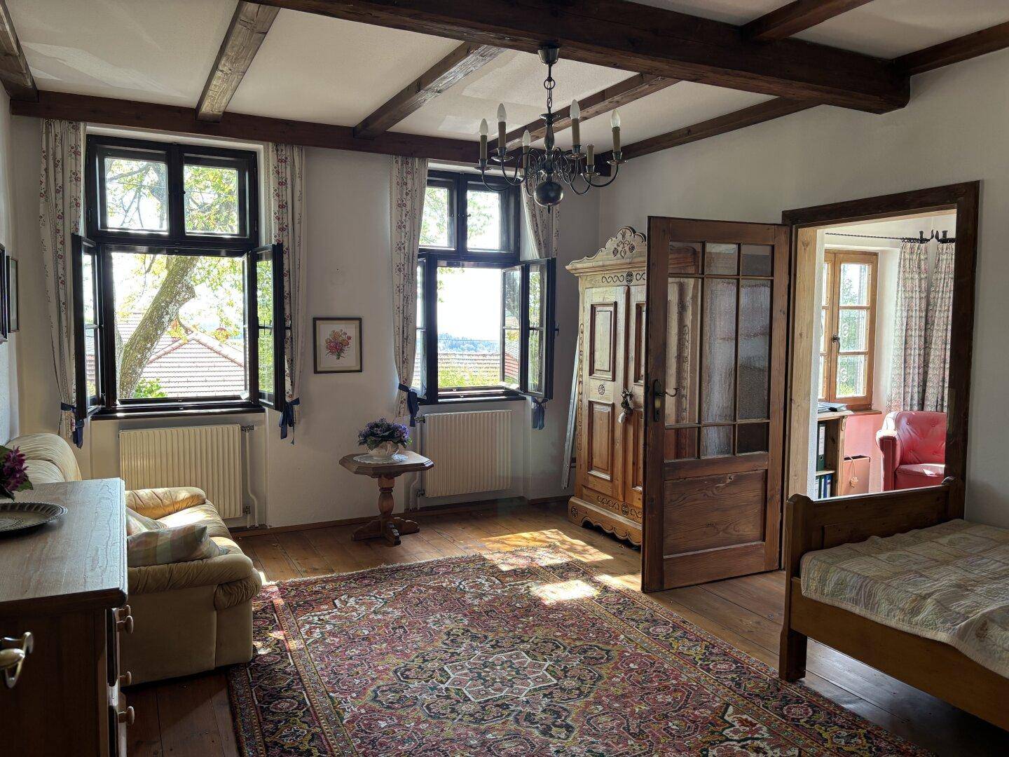 Geräumiges Schlafzimmer mit Holzboden, sichtbaren Deckenbalken und traditionellen Holzmöbeln.