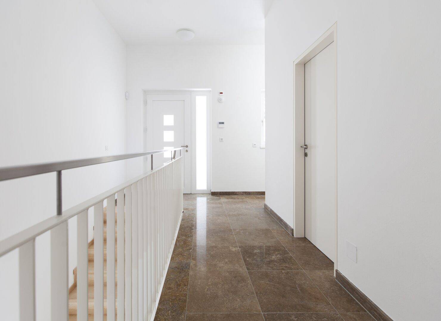Heller Flur im Obergeschoss mit Fliesenboden und Zugang zu weiteren Räumen und Treppe.