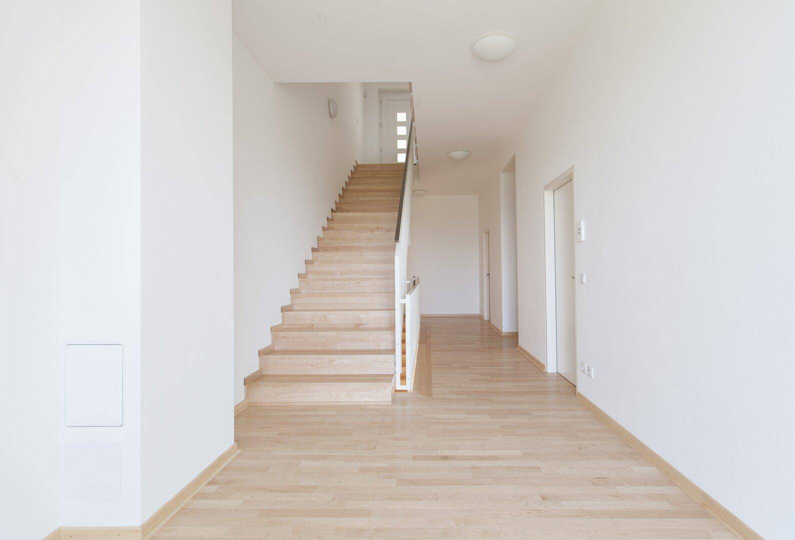 Heller Flur mit Holztreppe und Holzboden, der zu den oberen Stockwerken des Hauses führt.