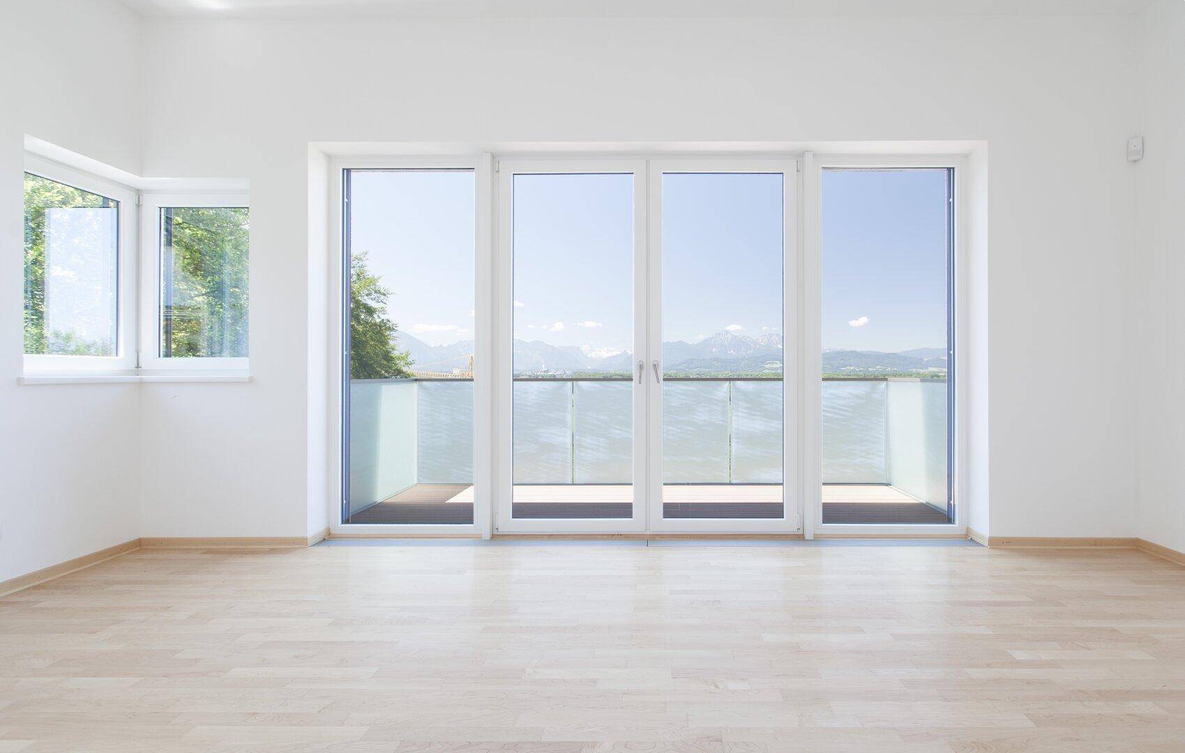 Großzügiger, heller Raum mit Holzboden und Panoramafenstern, die einen weiten Bergblick bieten.