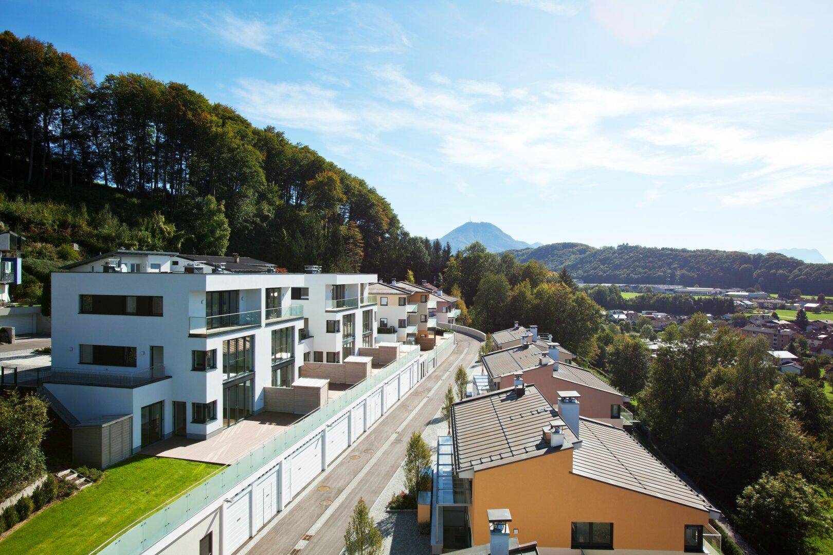 Moderne Wohnanlage in Hanglage mit Blick auf die umliegende Landschaft und Berge.