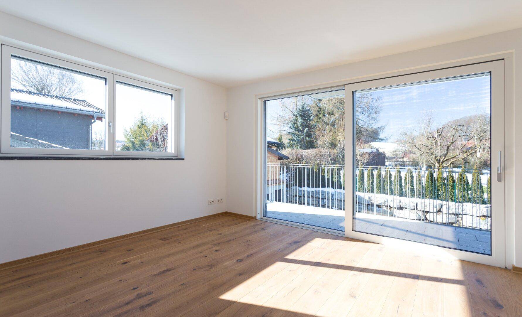 Heller Raum mit Holzboden und großer Schiebetür zum Balkon, bietet viel Tageslicht.