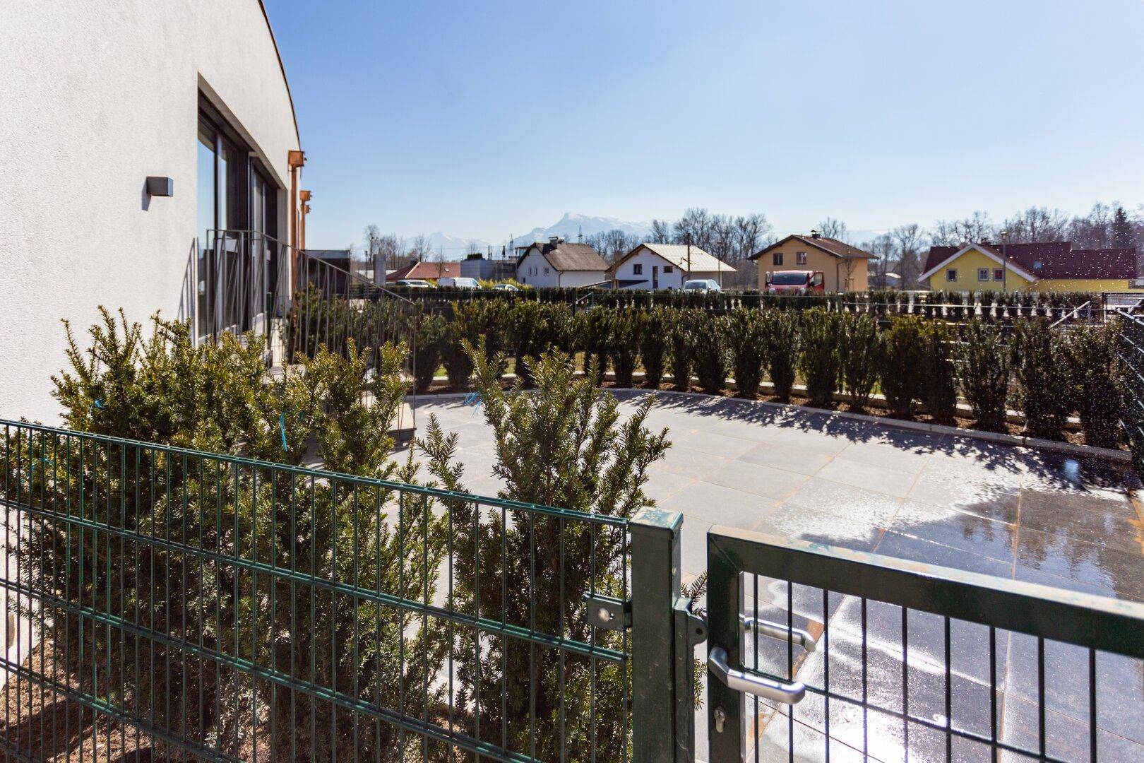 Außenansicht des Gebäudes mit gepflegter Hecke und Blick auf die Umgebung.