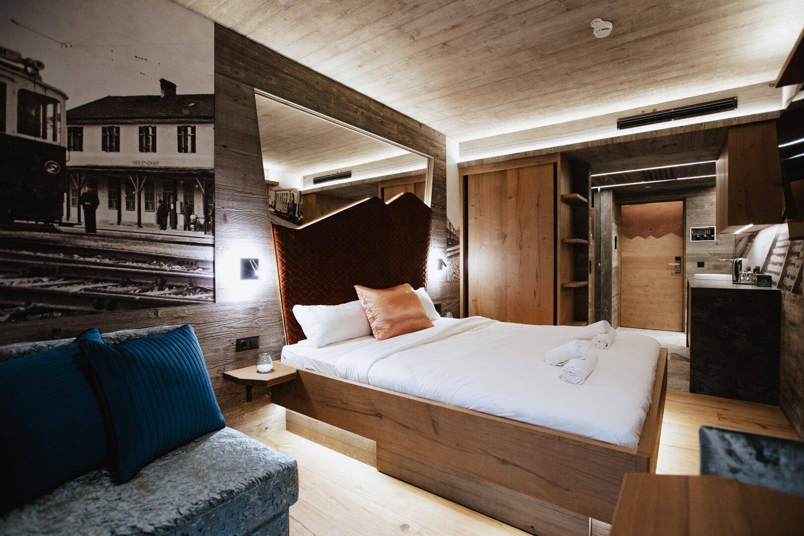 Modernes Schlafzimmer mit Holzwänden und -decke, einem großen Bett und indirekter Beleuchtung für eine gemütliche Atmosphäre.
