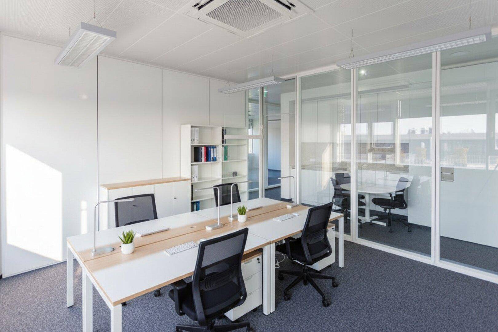 Helles und modernes Büro mit mehreren Arbeitsplätzen, Glaswänden und integrierter Klimaanlage.