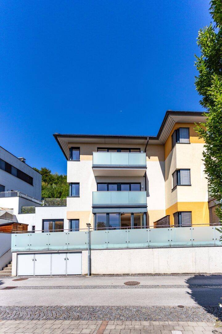 Moderne Wohnanlage mit Garagenzufahrt, Balkonen und Glasgeländern.