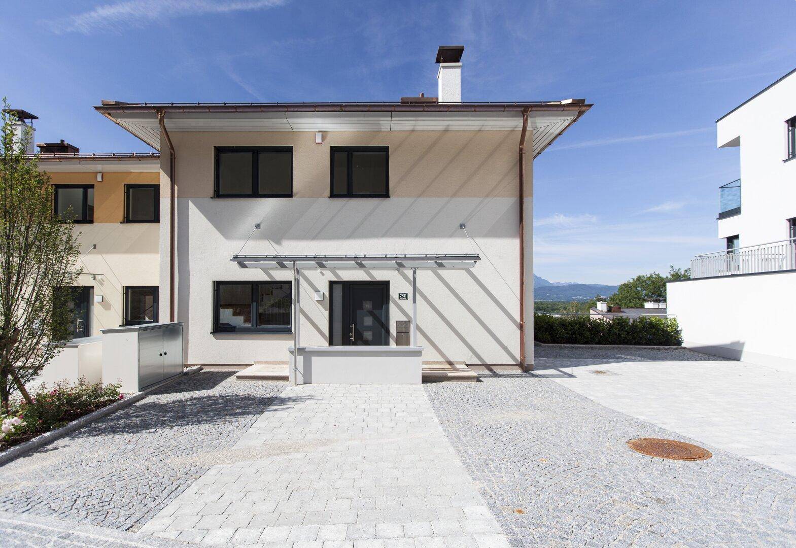 Eingangsbereich eines modernen Hauses mit gepflastertem Vorplatz und klarem Design.