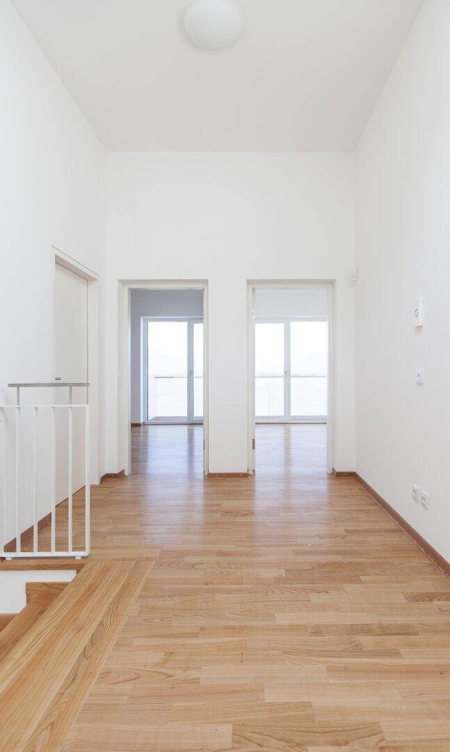 Heller Flur im Obergeschoss mit Holzboden und Zugang zu weiteren Zimmern.