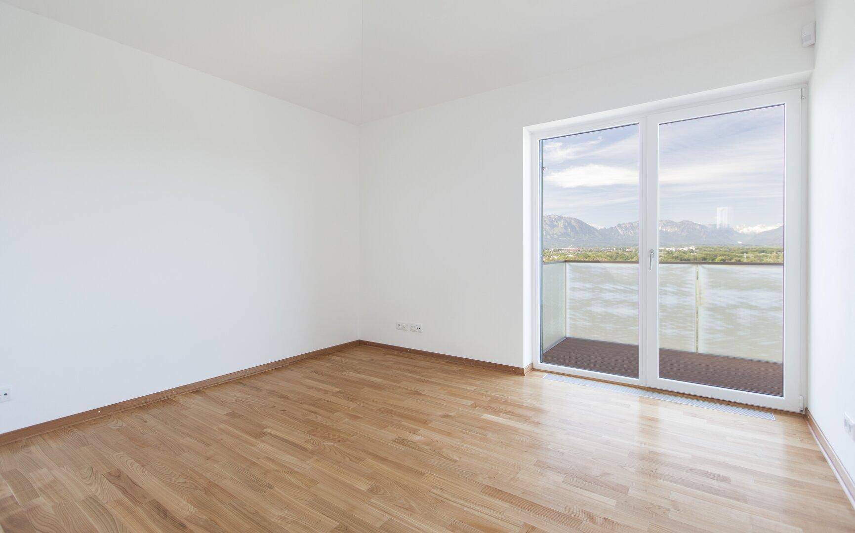 Geräumiges Schlafzimmer mit Holzboden, großen Fenstern und Panoramablick auf die Berge.