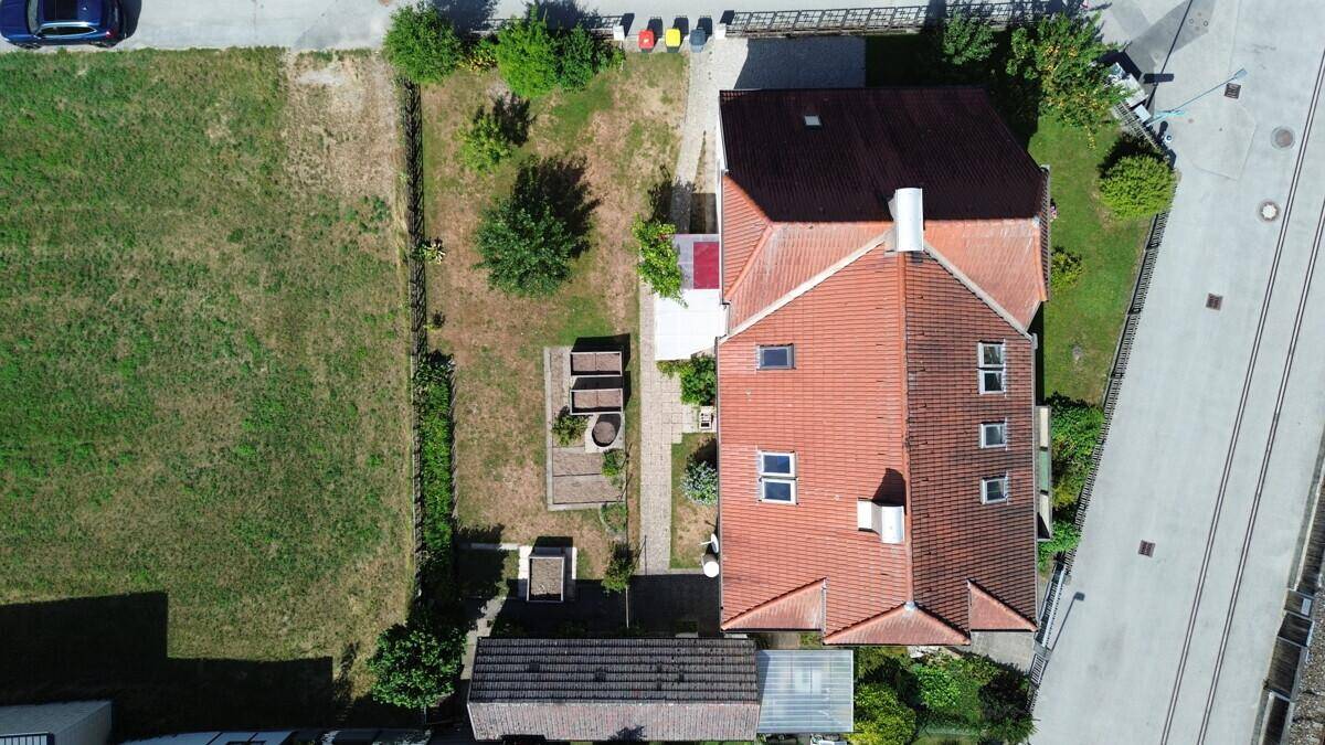 Draufsicht auf das Grundstück mit Haus, Gartenbereich und angrenzender Grünfläche.