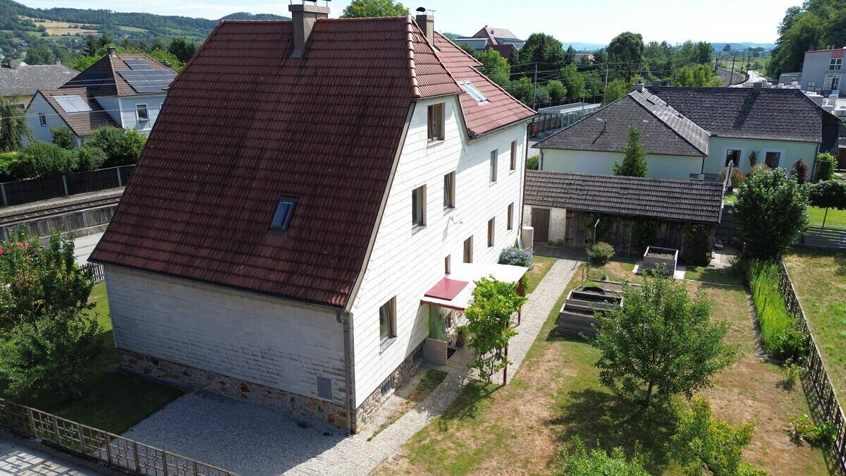 Seitenansicht des Hauses mit großem Garten, Schuppen und Blick auf die grüne Umgebung.