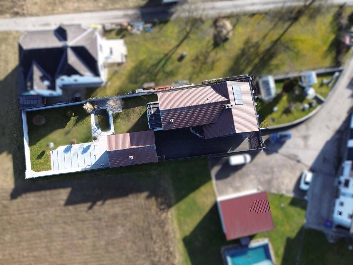 Vogelperspektive des Grundstücks mit Wohnhaus, Gartenanlage und angrenzenden Feldern.